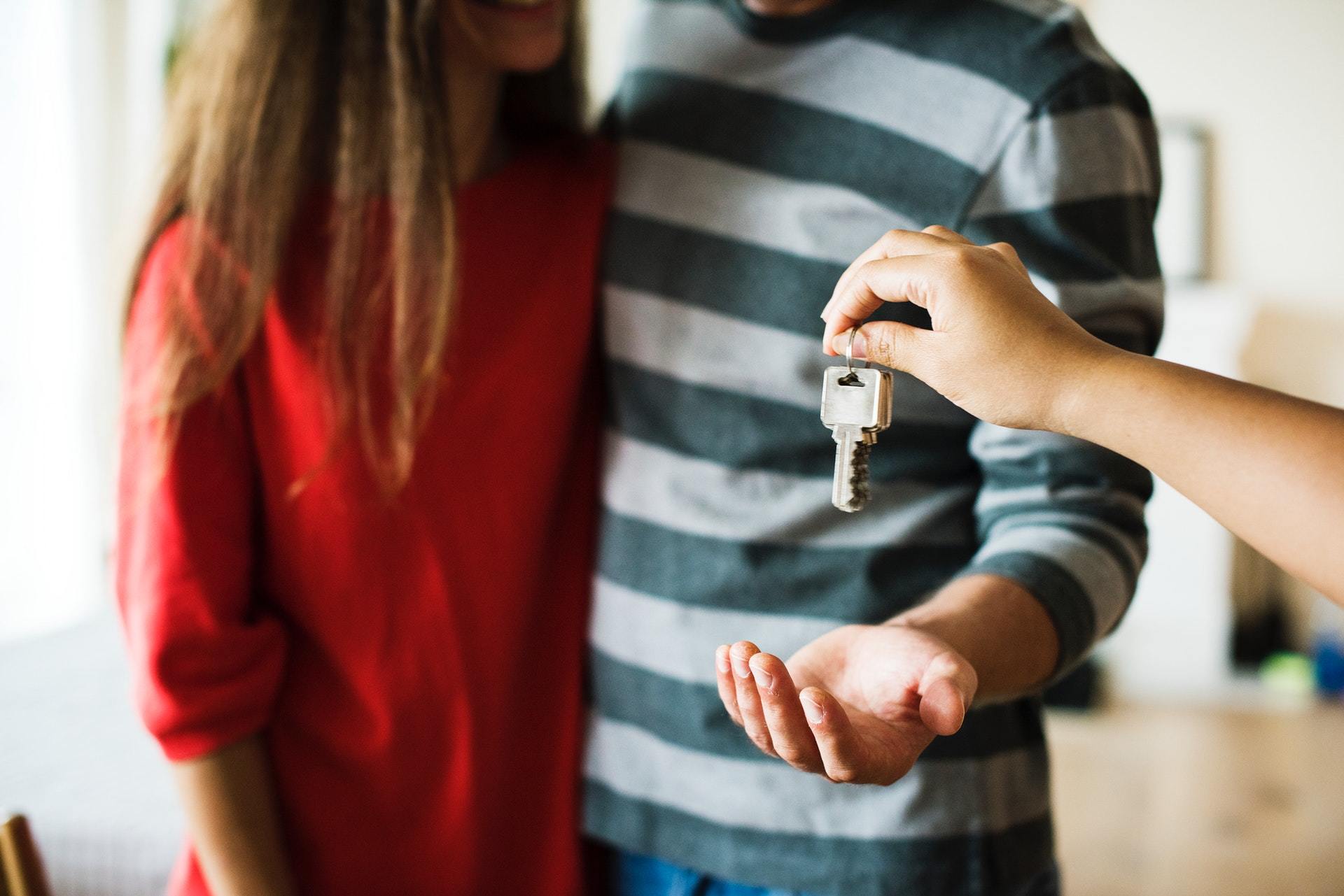 Couple getting keys to home following reading beginners guide to mortgages in the UK